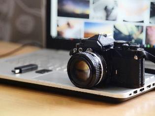 A digital camera sitting on top of a laptop.