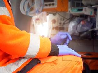 An emergency medical person in full garb, sitting inside an ambulance.