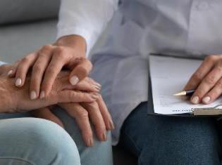 A person with a clip board holding another person's hands.