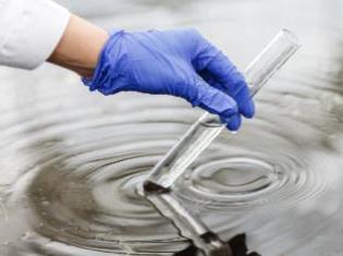 A person taking a test tube sample from a pool of water.